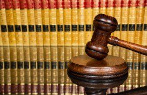 A wooden judge 's gavel is sitting in front of a row of books.