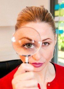 A woman in a red shirt is looking through a magnifying glass