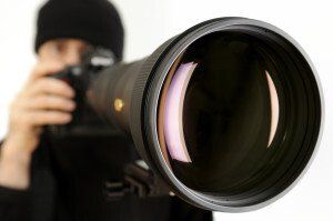 A man in a black hat is taking a picture with a camera.