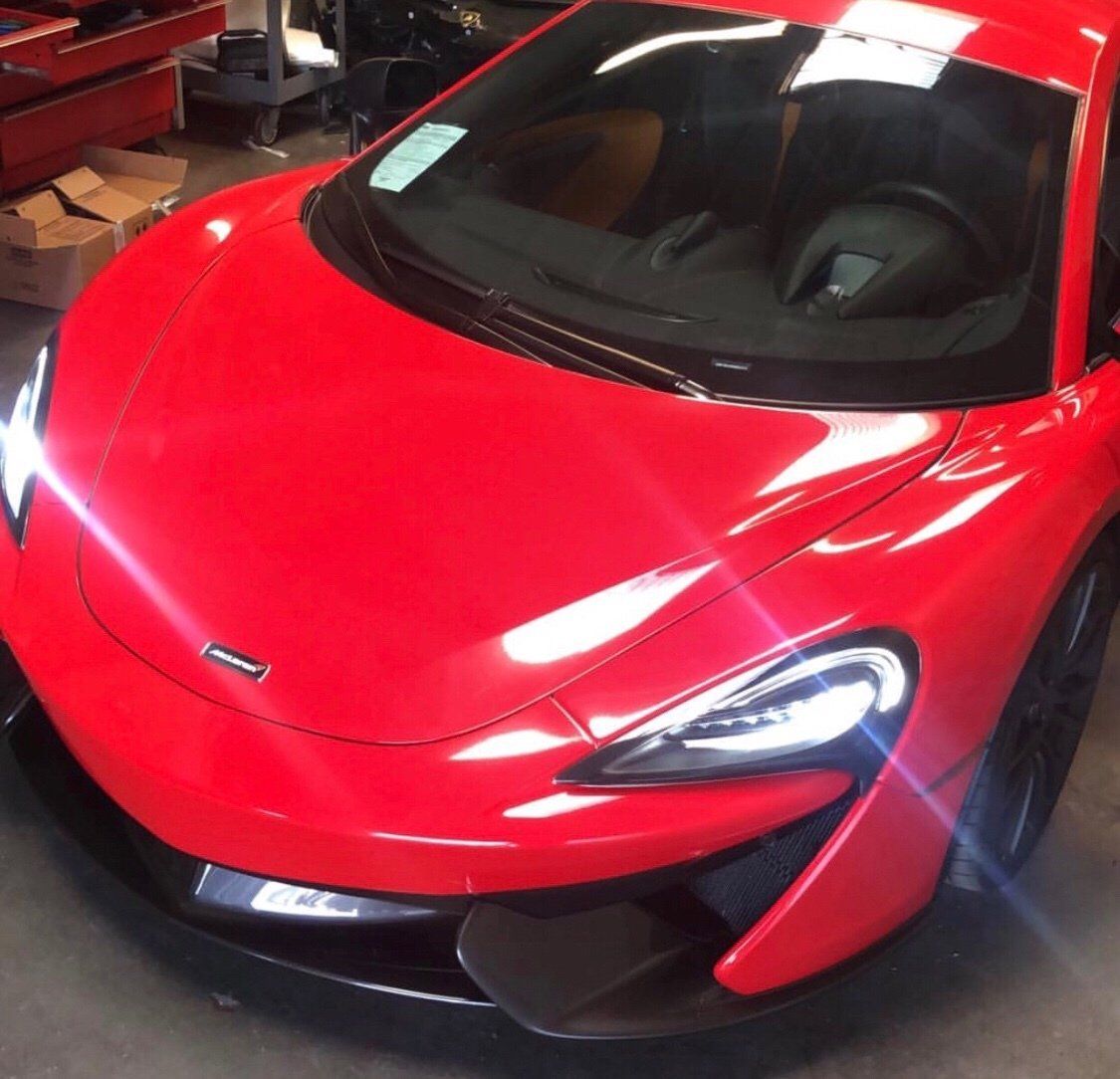 A red mclaren sports car is parked in a garage