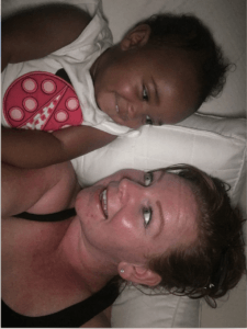 A woman and a baby are laying on a bed