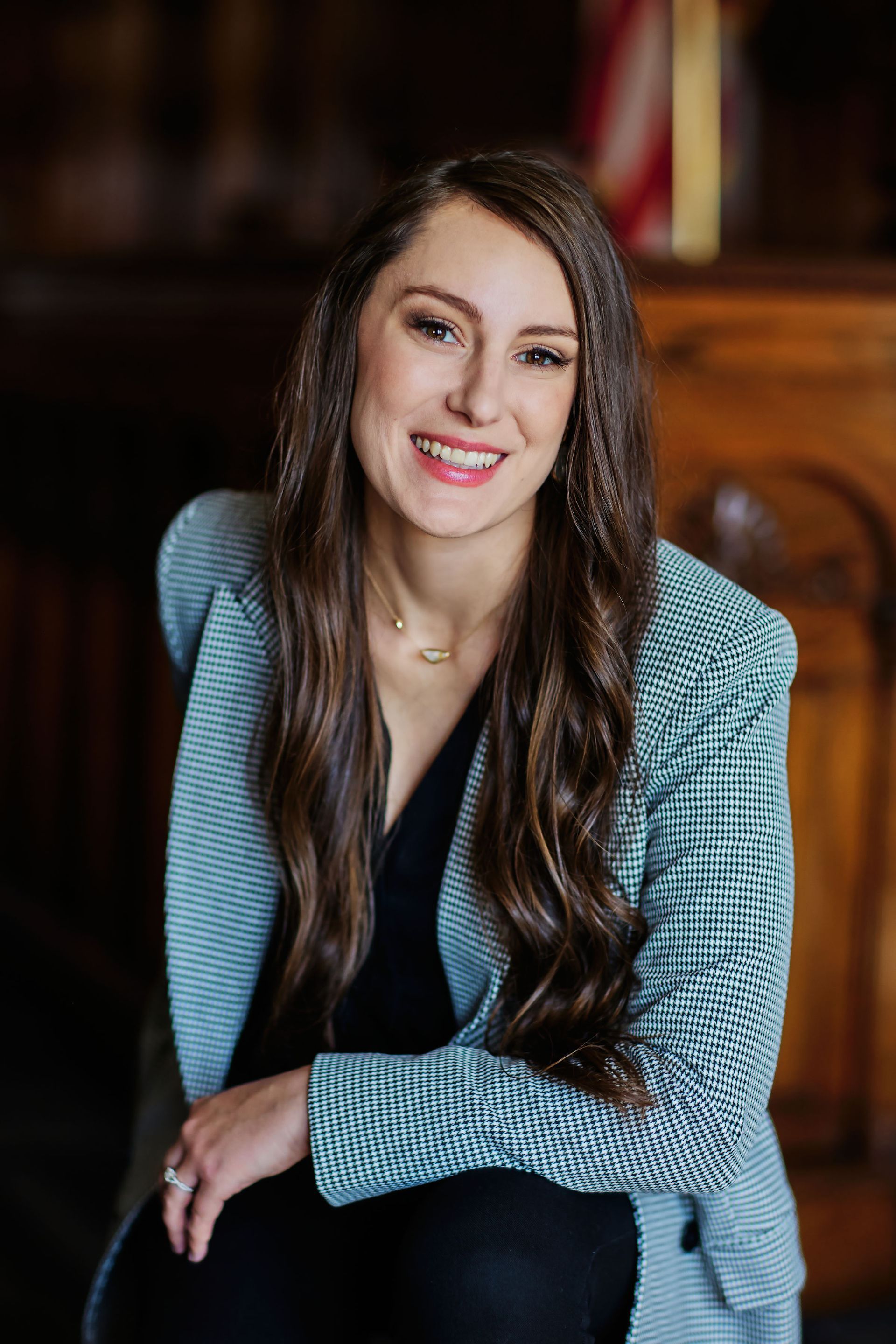 Smiling woman in a blue patterned blazer seated against a blurred indoor background