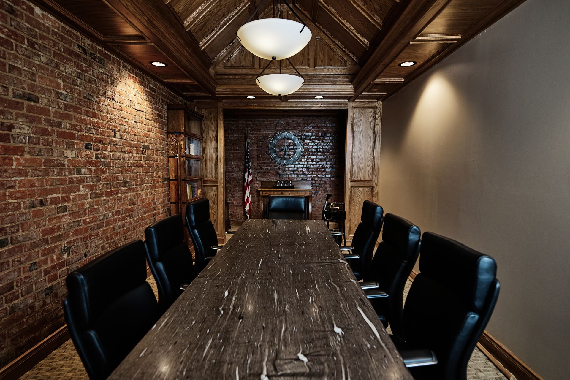 Conference room with brick wall, long table, leather chairs, and fireplace.