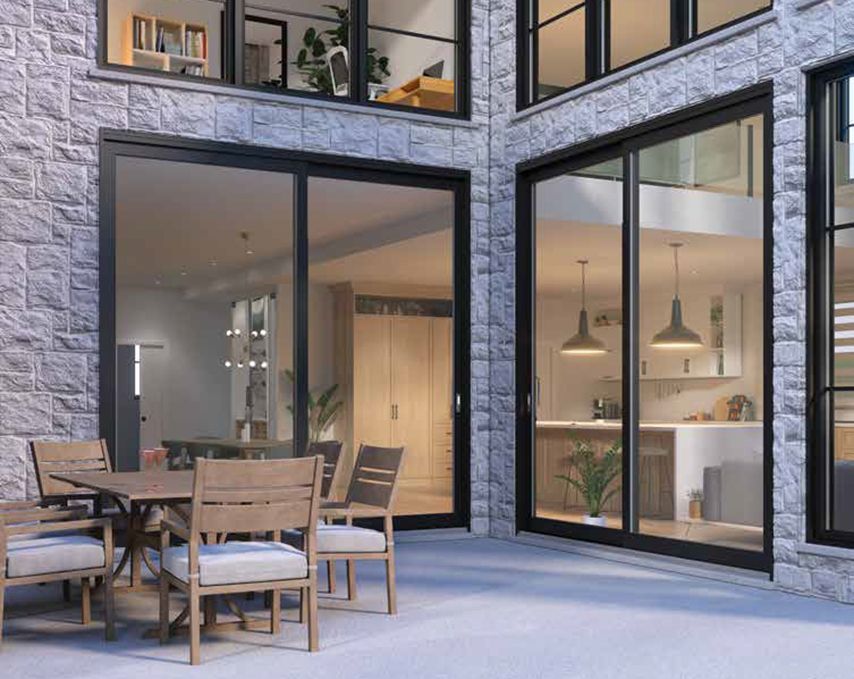 Terrasse avec mobilier de jardin jouxtant de grandes portes coulissantes en verre d'une maison moderne.