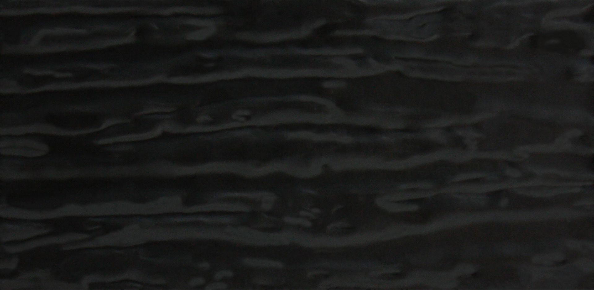 Surface texturée sombre, probablement en bois ou en pierre, avec des lignes horizontales et de subtiles variations de teinte.