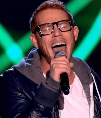 Man with red hair and glasses singing