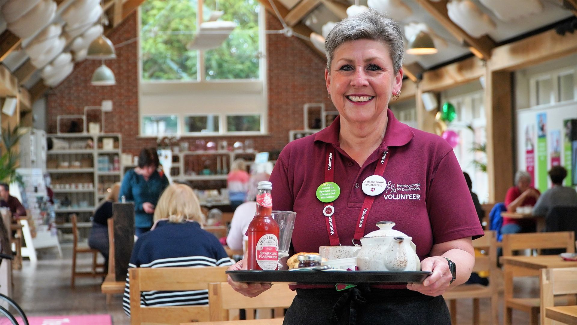 Front of House volunteer at The Grange restaurant, Anne Burton with a tray of tea and cakes.