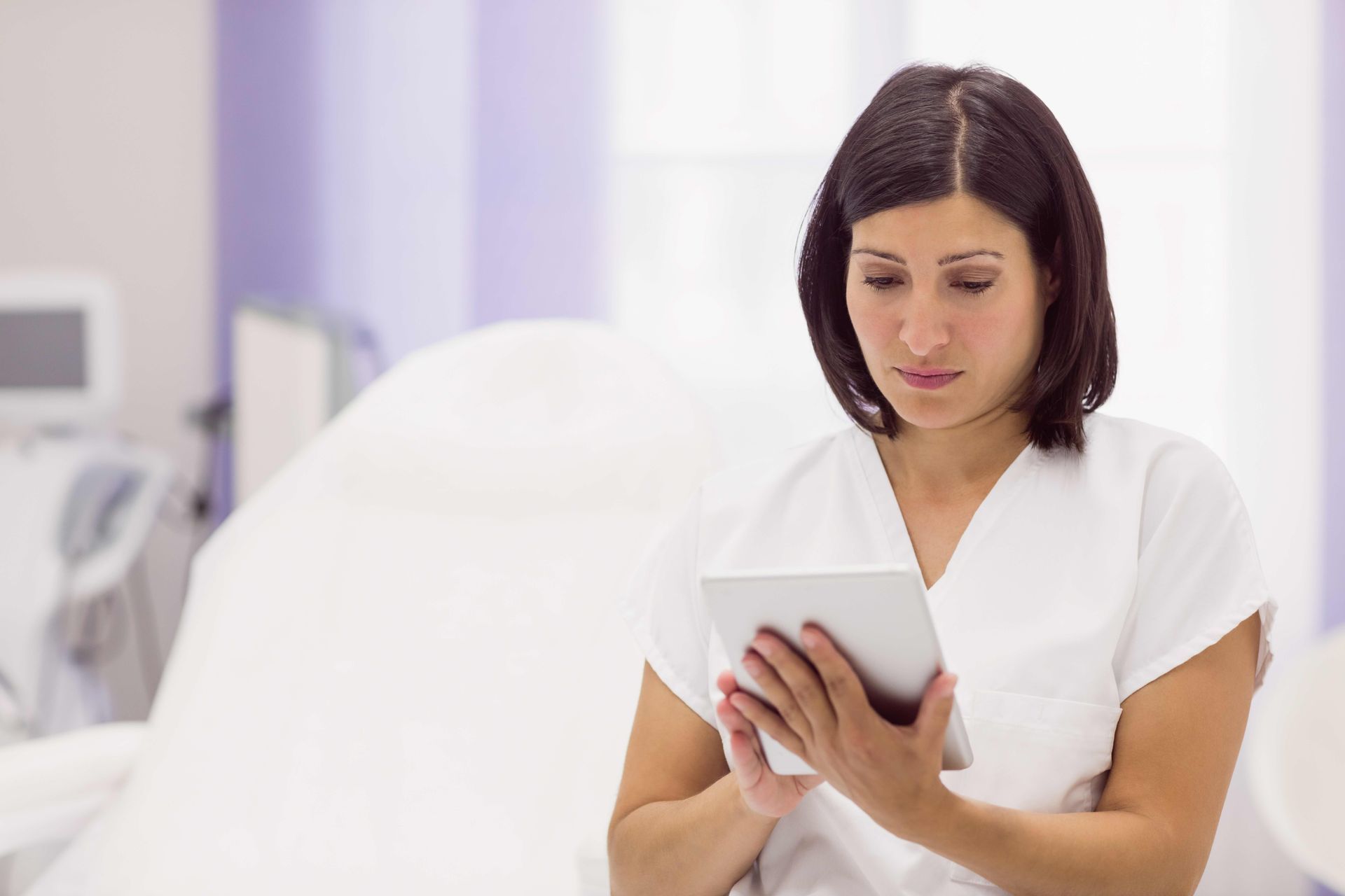 a nurse is using a tablet computer in a hospital room .