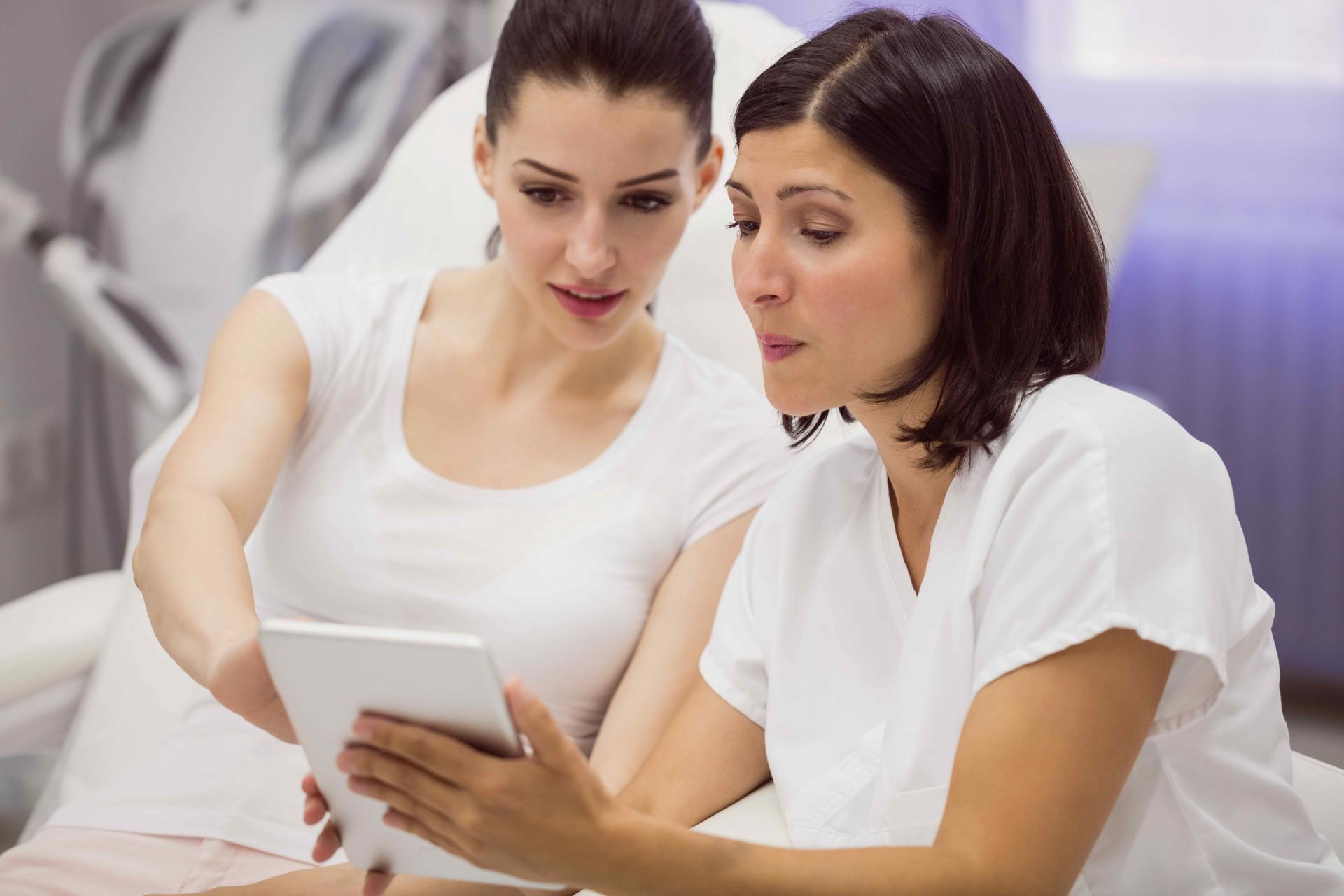 two women are looking at a tablet together .