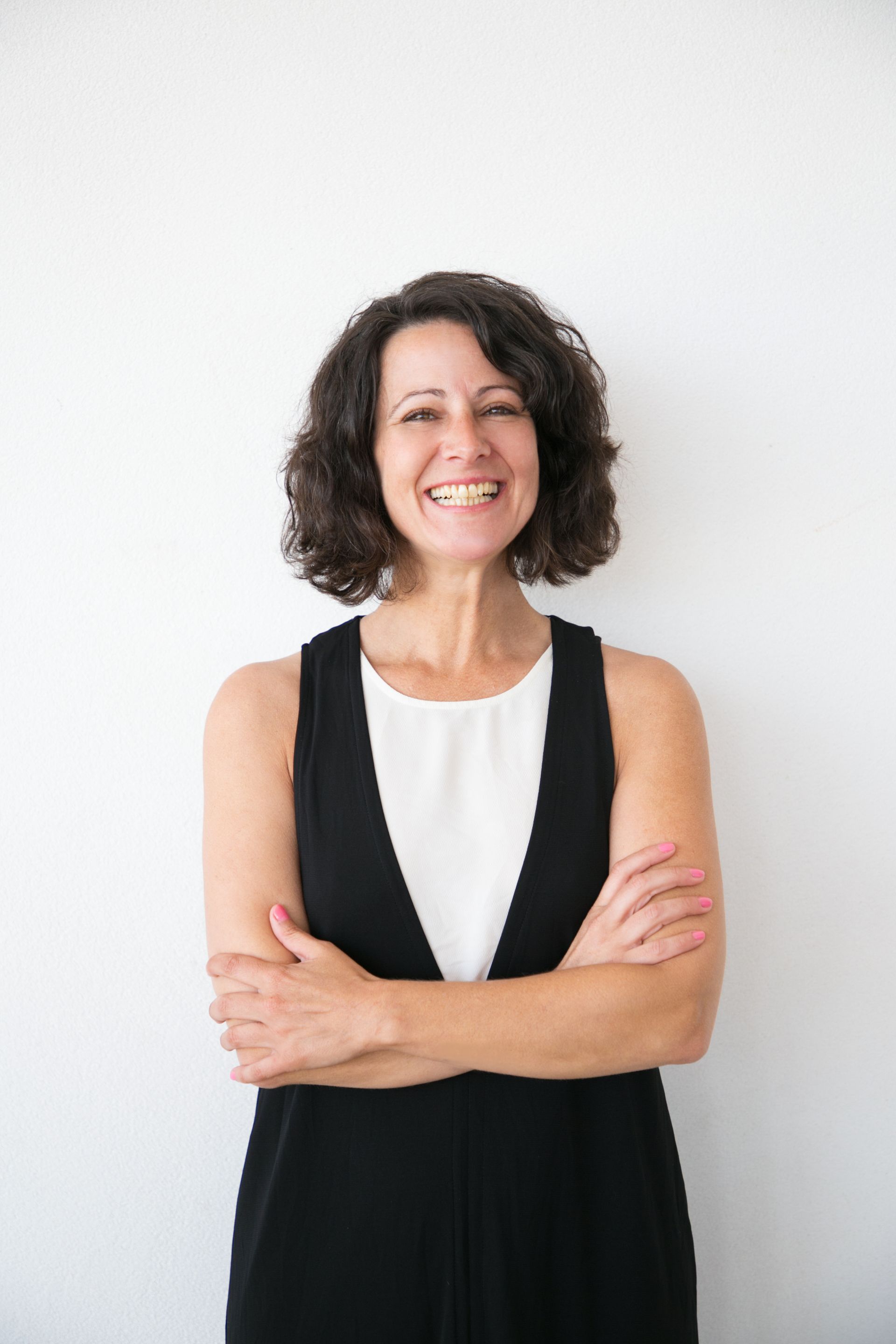a woman in a black and white dress is smiling with her arms crossed .