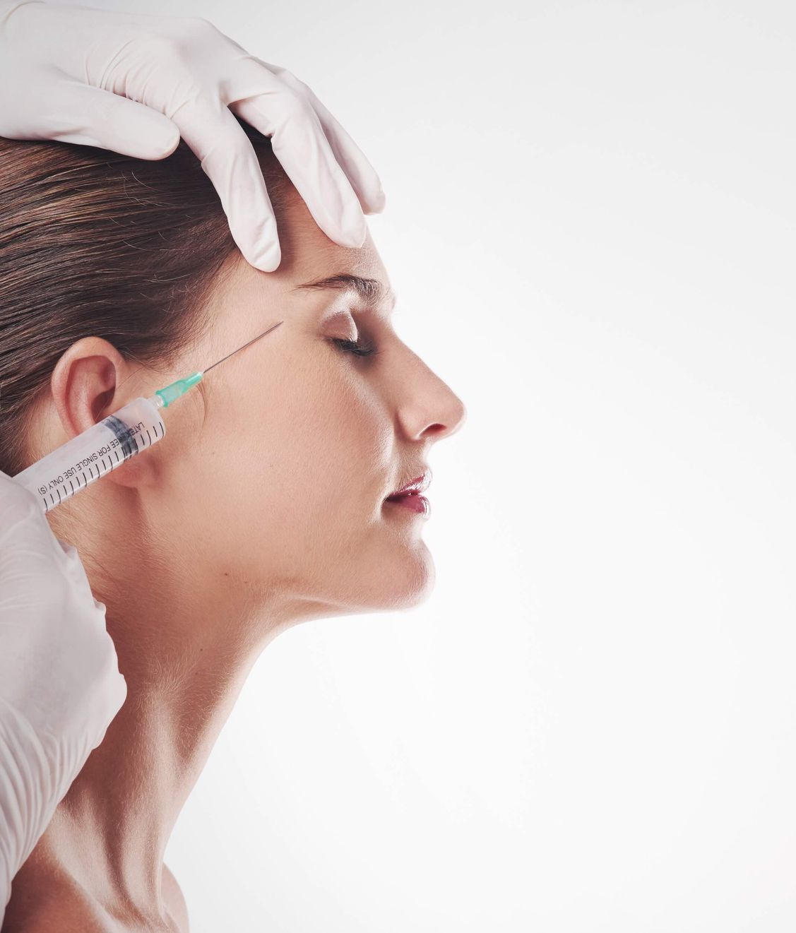 a woman is getting a botox injection in her forehead .