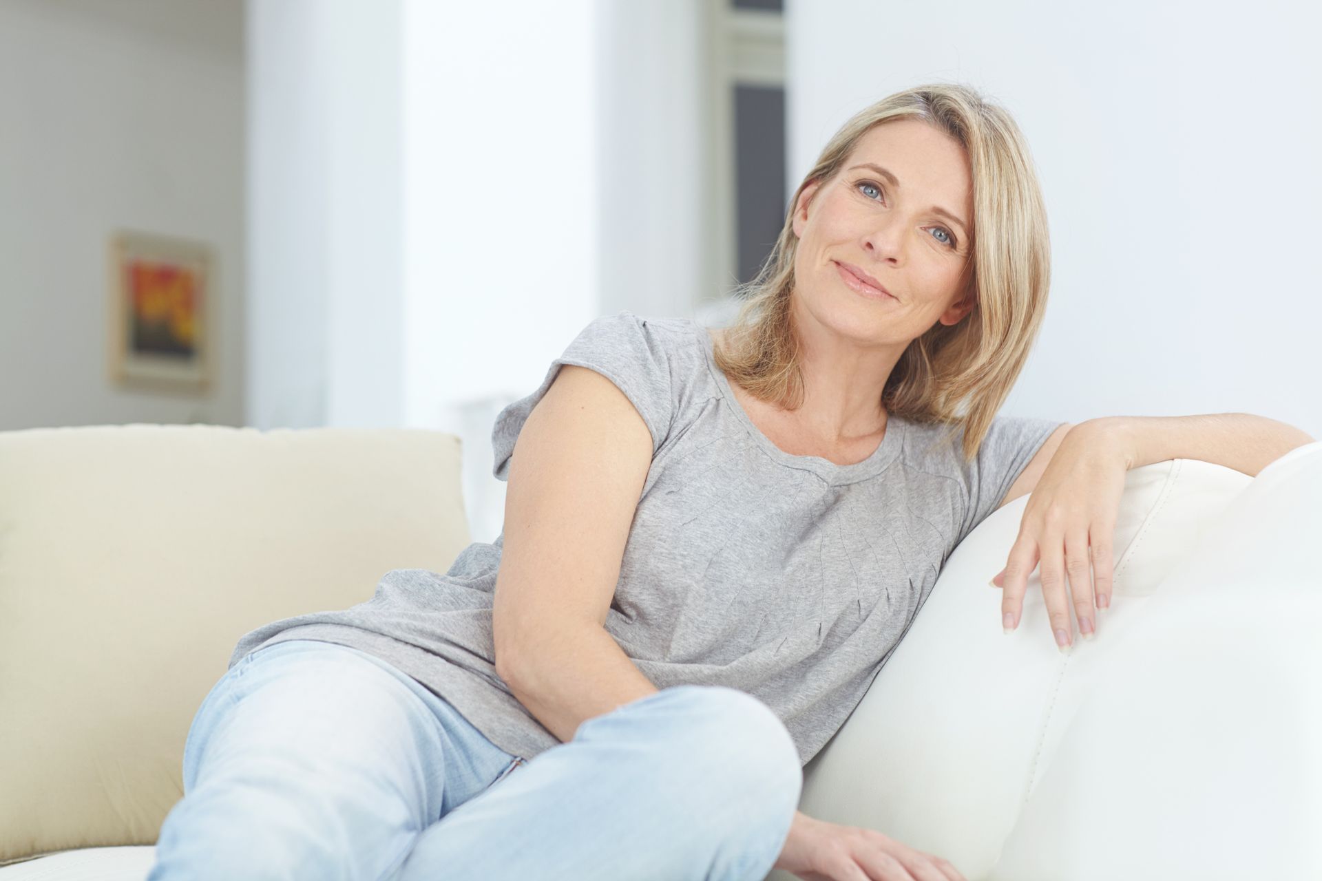 a woman is sitting on a couch with her legs crossed and smiling .