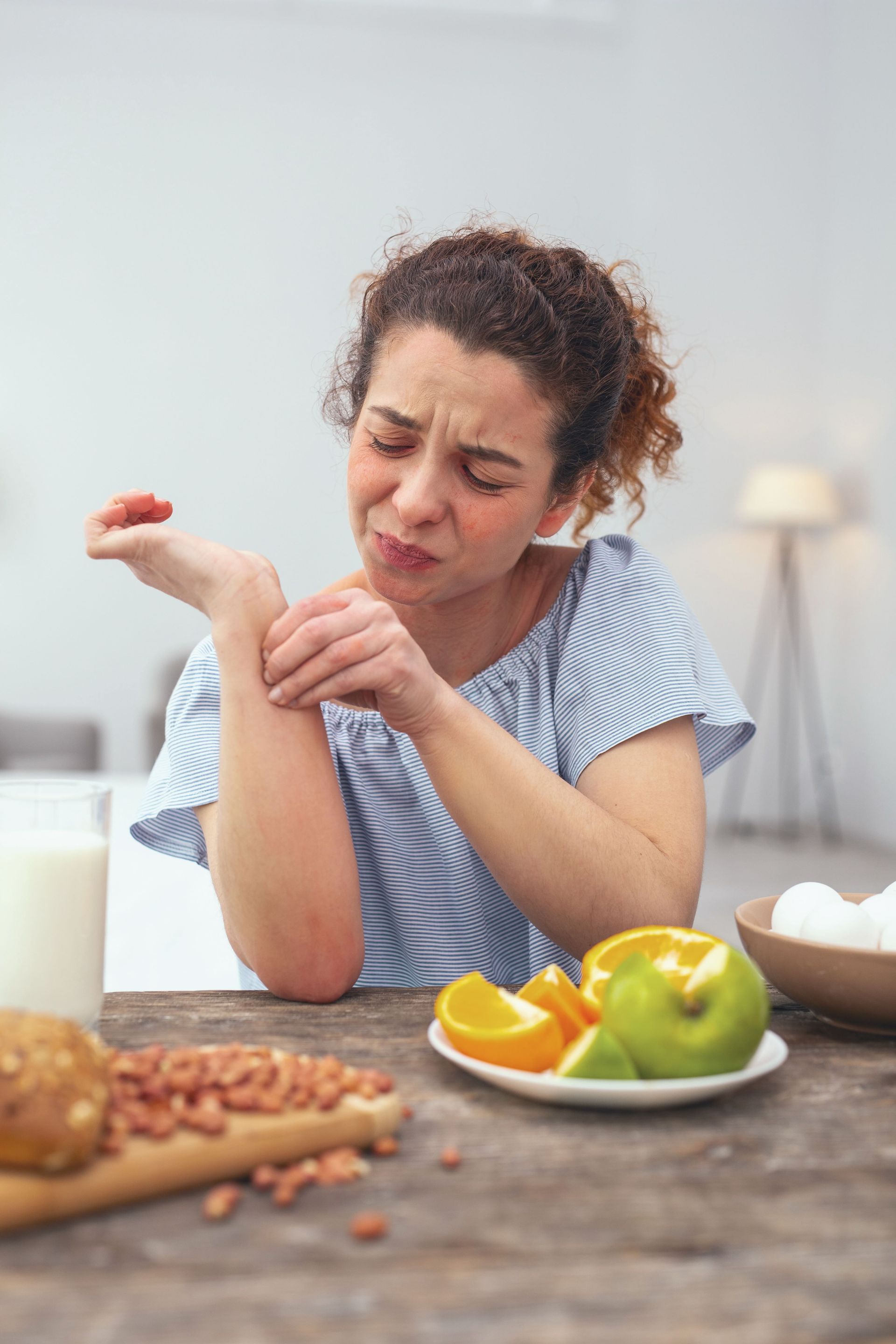 a woman is sitting at a table scratching her wrist .