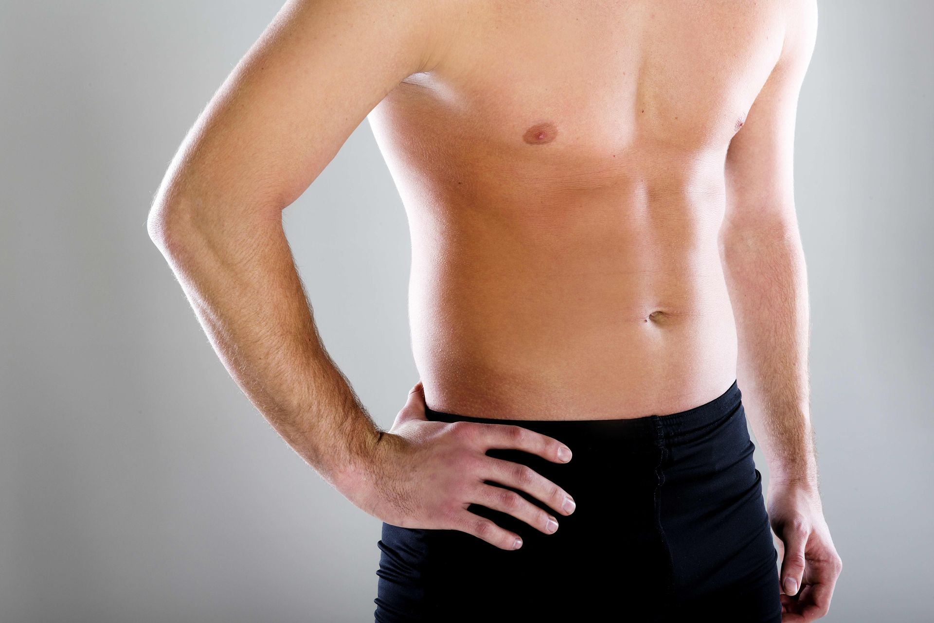 a shirtless man is standing with his hands on his hips .