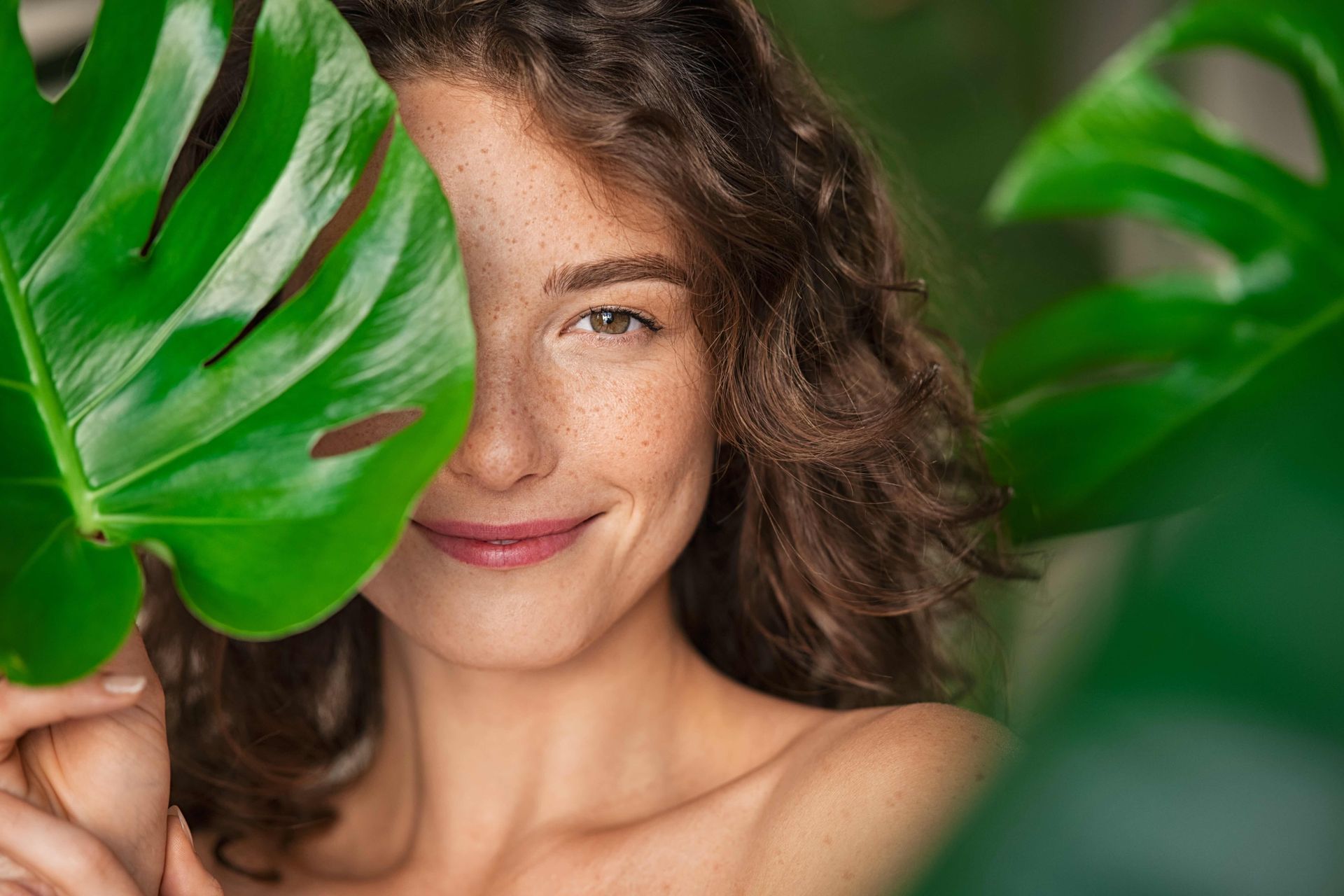 a woman is covering her face with a green leaf .
