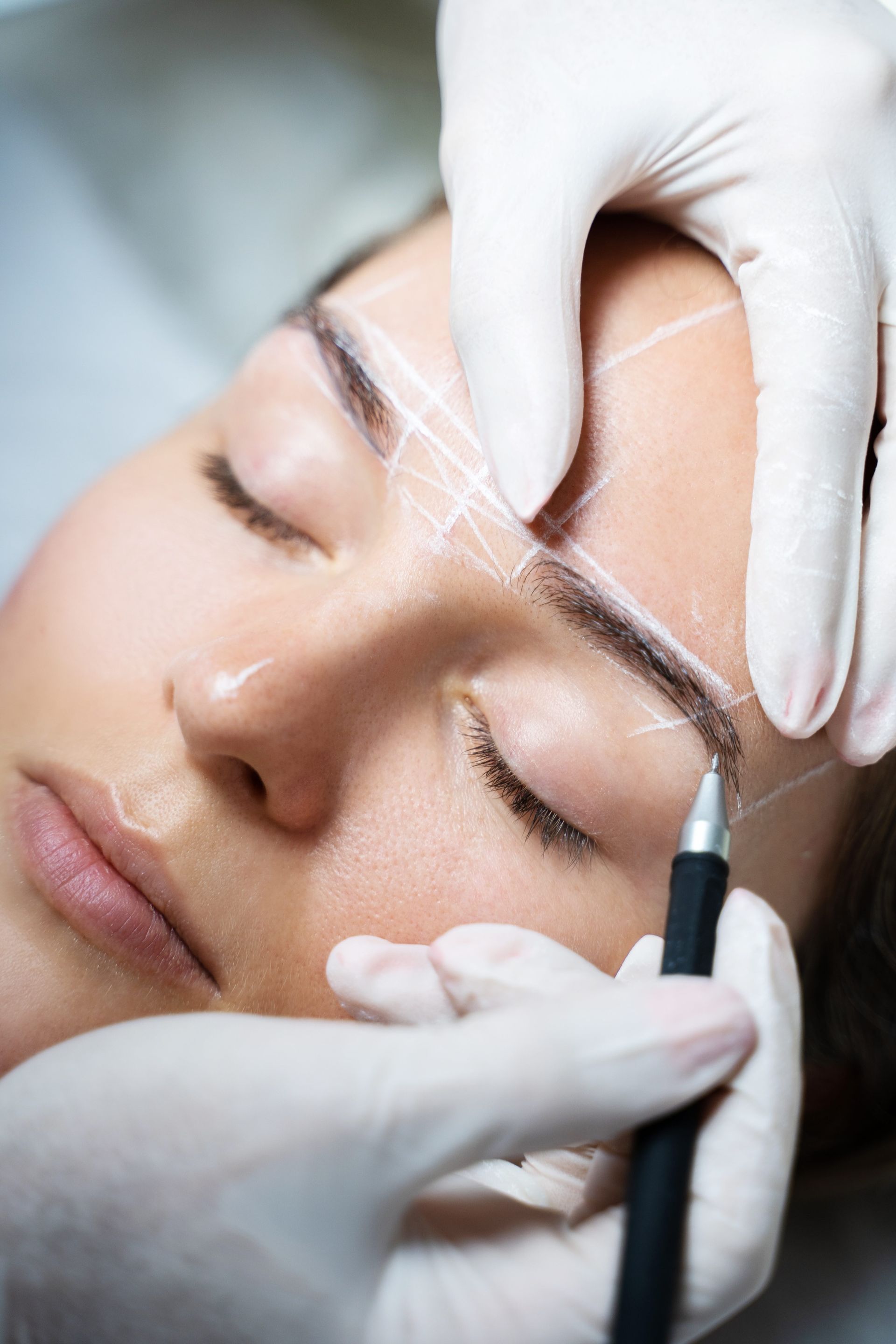 a woman is getting her eyebrows drawn by a tattoo artist .
