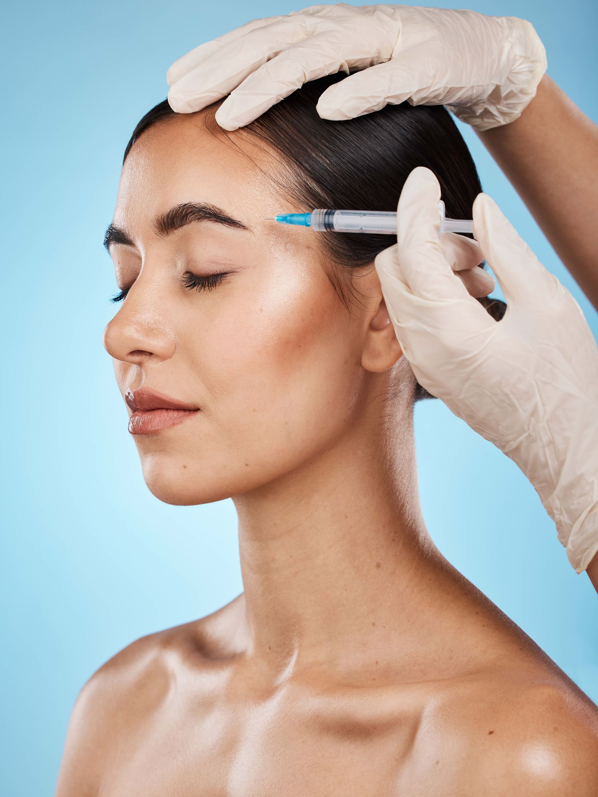 a woman is getting a botox injection in her forehead .
