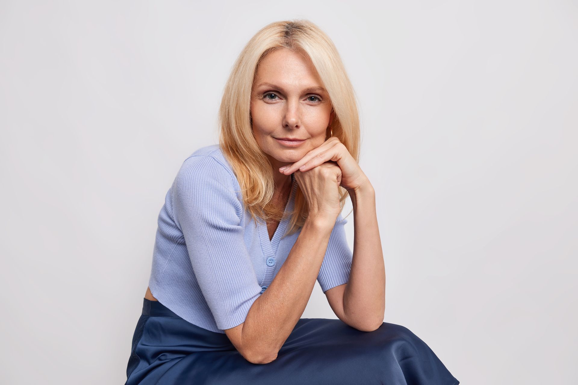 a woman is sitting on the floor with her hands on her chin .