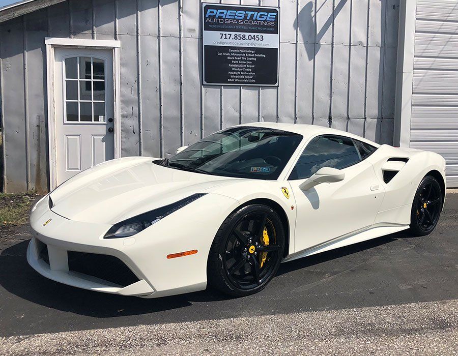 A white ferrari 488 gtb is parked in front of a building.