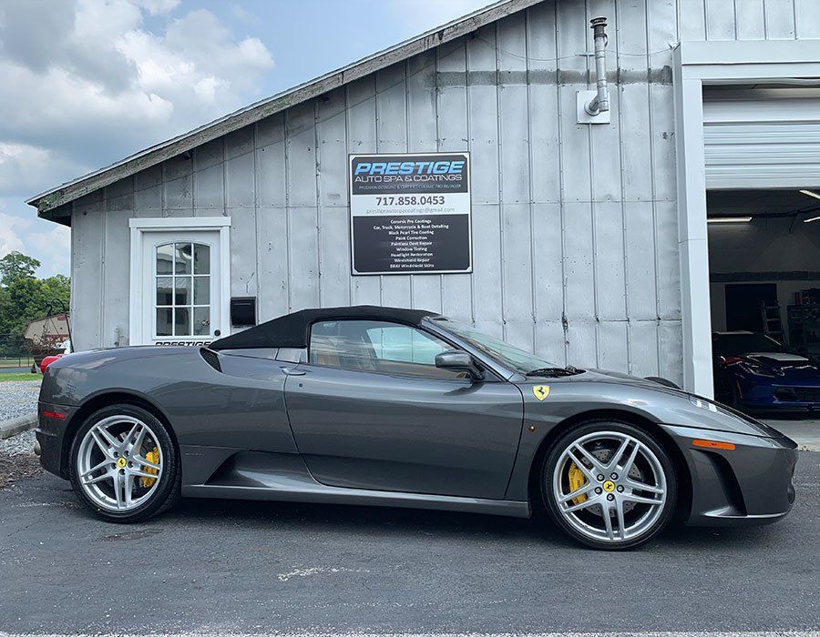 A gray sports car is parked in front of a garage.