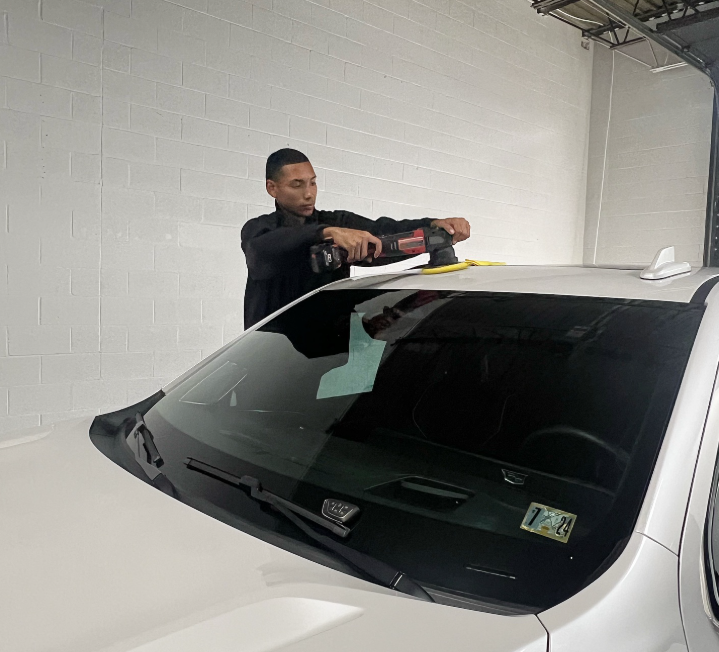 A man is polishing the roof of a white car