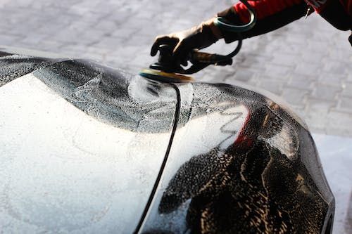 A person is polishing a car with a machine.