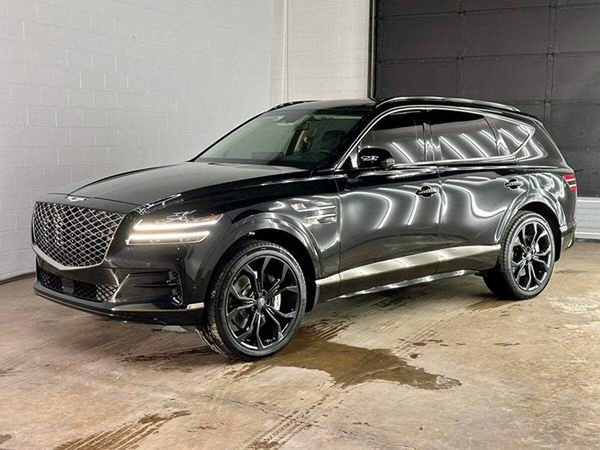 Black Genesis GV70 SUV parked indoors with black rims, glossy paint.