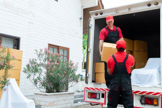 Two men are loading boxes into a moving truck.