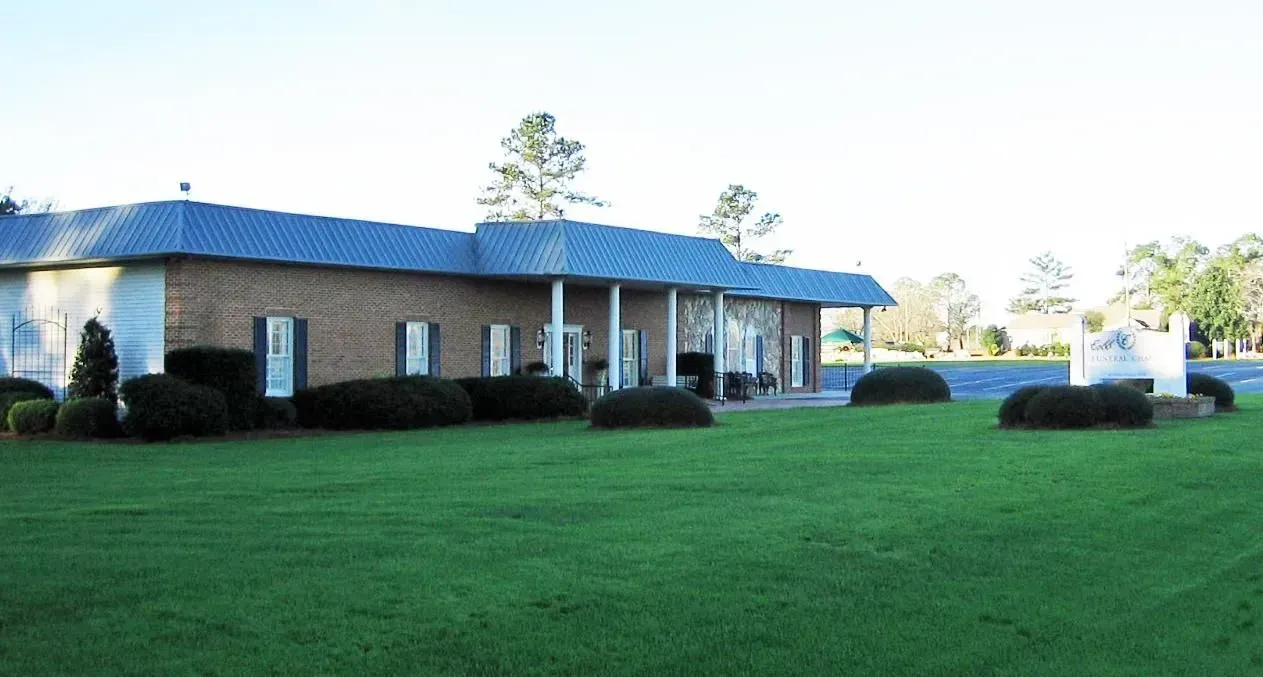 Brick building with American flag and sign reading “Palmer-Marler” on a sunny lawn.