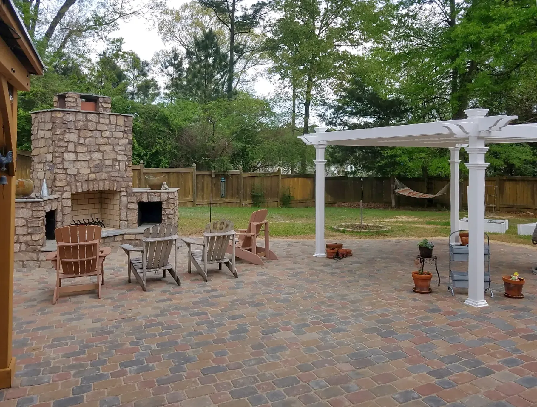 A Stone Work Patio With A Fireplace, Chairs, Tables And A Pergola - Raymond, MS - Parker Roofing & Remodeling
