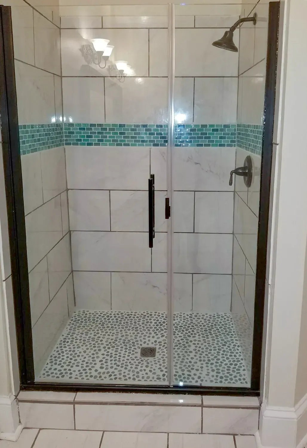A Shower Stall With A Glass Door And A Shower Head - Raymond, MS - Parker Roofing & Remodeling