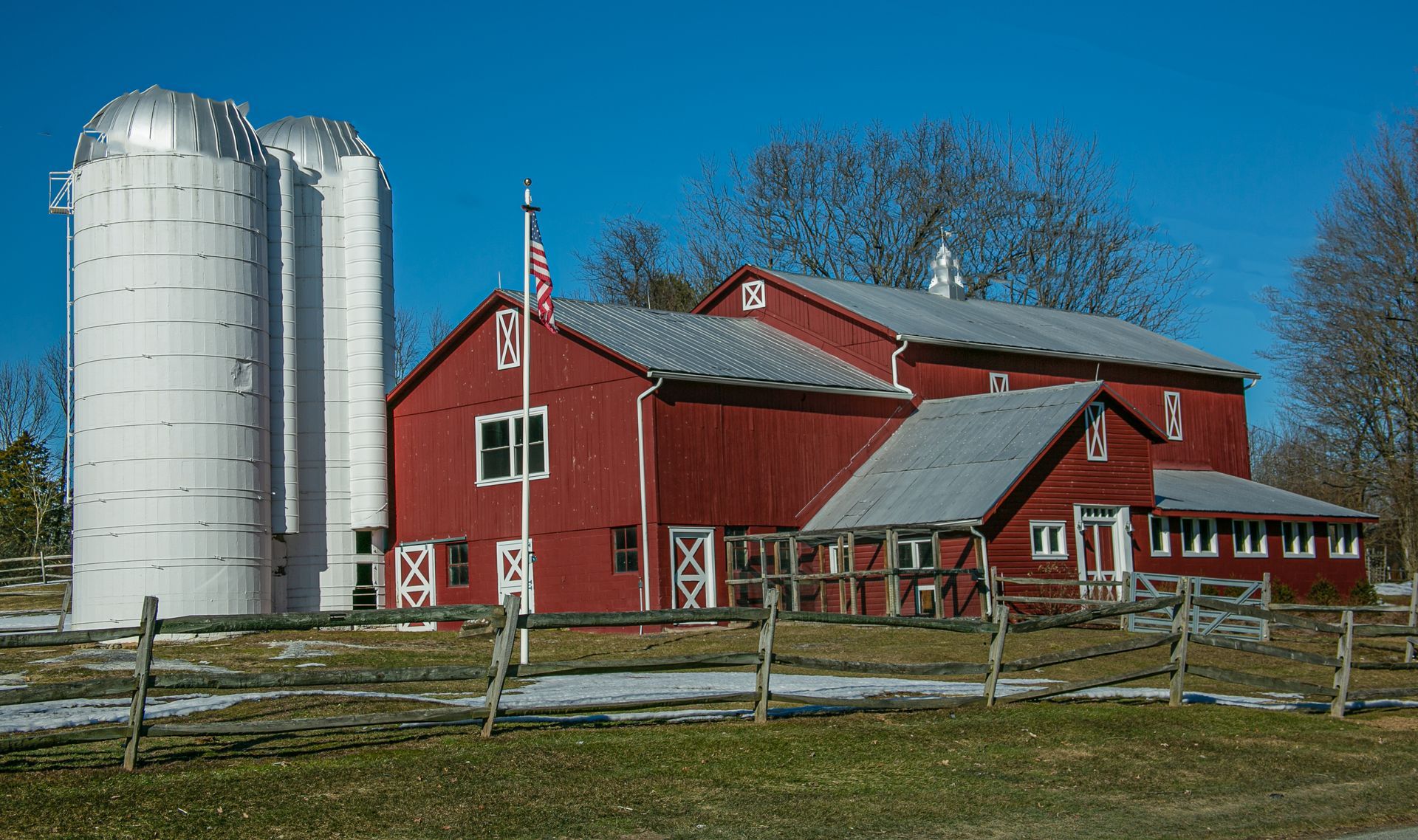 A red barn with two white silos in front of it