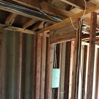 Wooden framing in a building undergoing renovation, showing exposed wall studs and an electrical box.