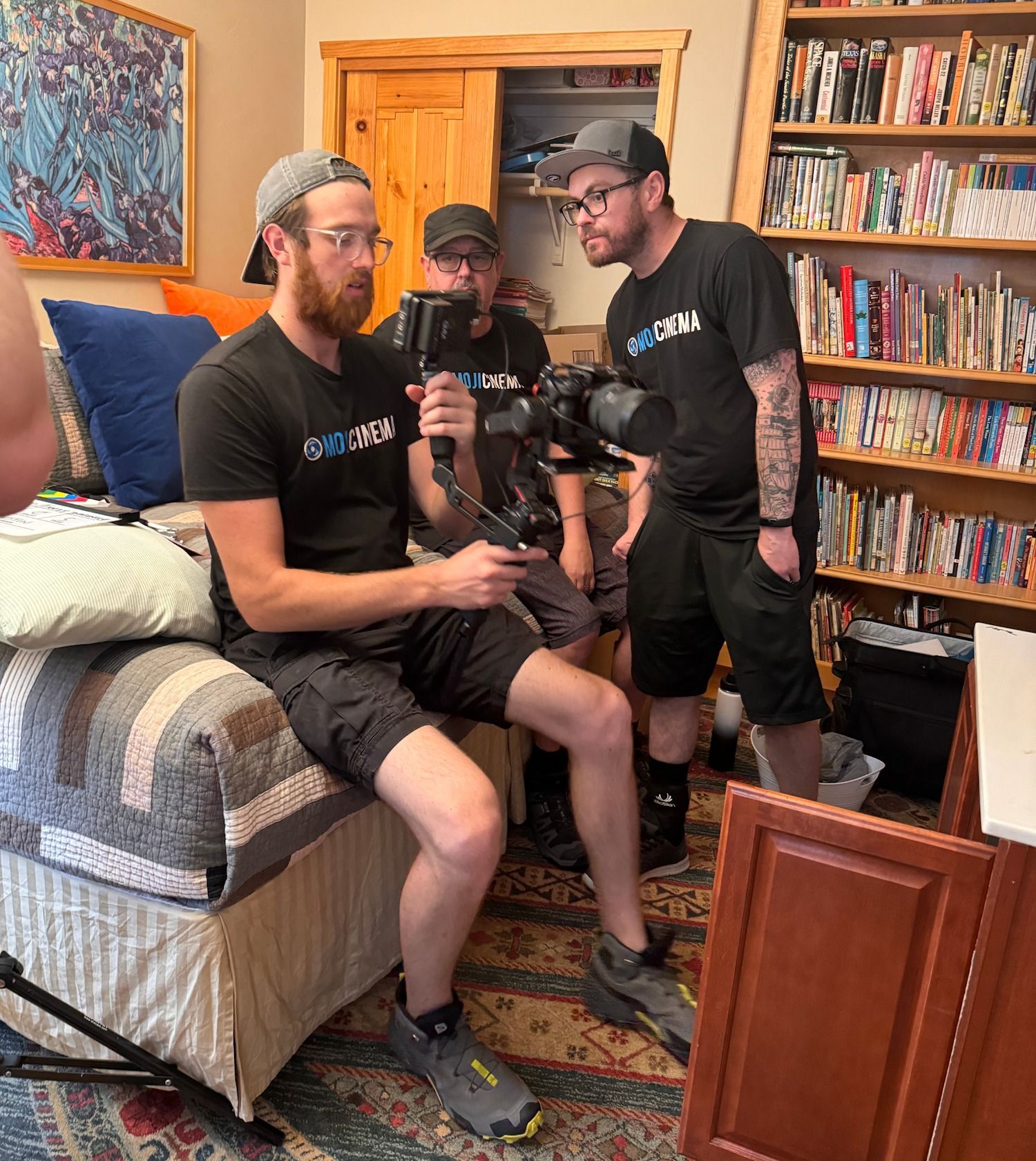 A group of men are sitting in a living room with one man holding a camera