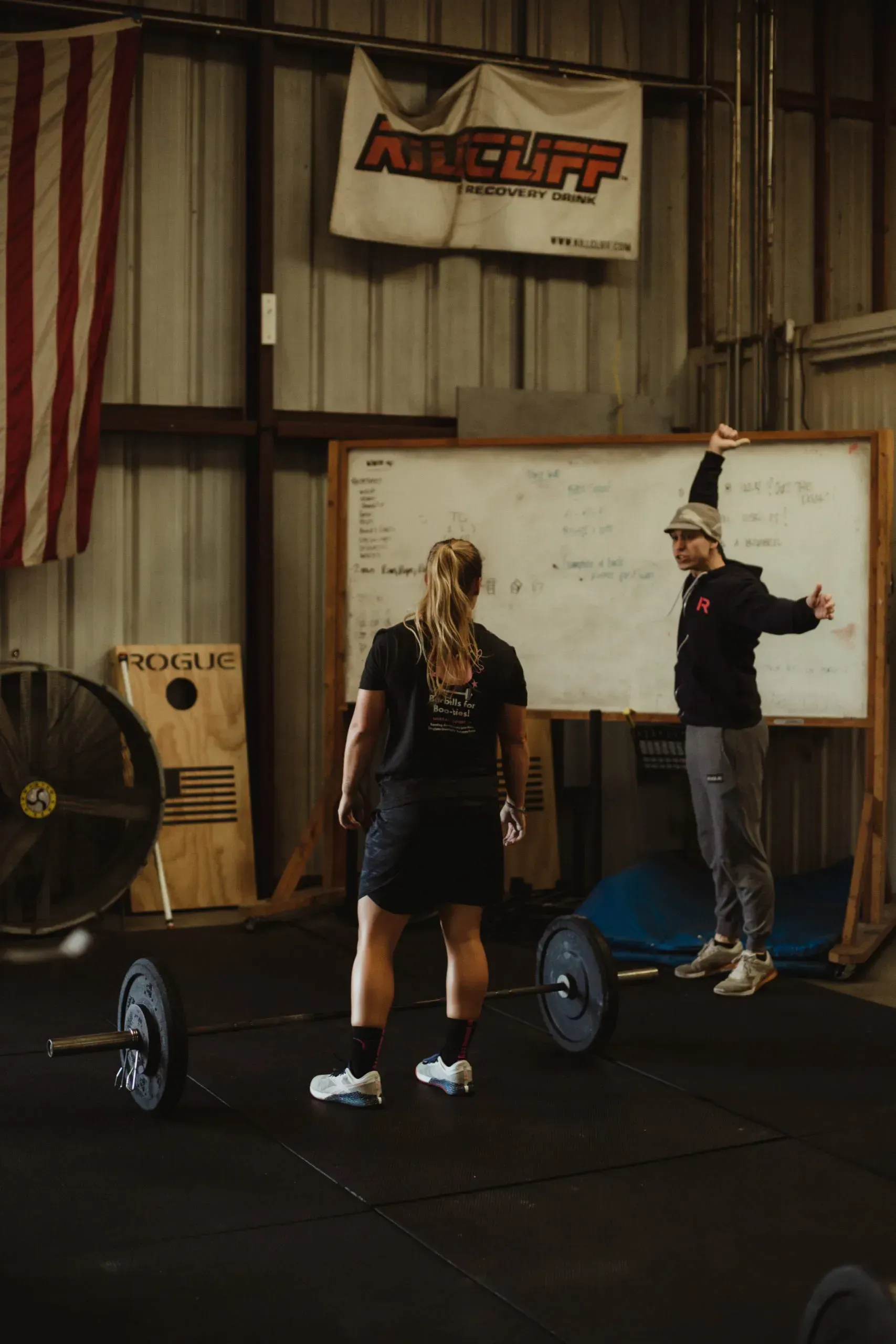A man is teaching a woman how to lift a barbell at Rose City Barbell Club gym in Thomasville, GA.