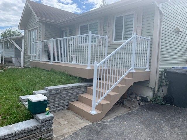 Une maison avec une terrasse et des escaliers devant.