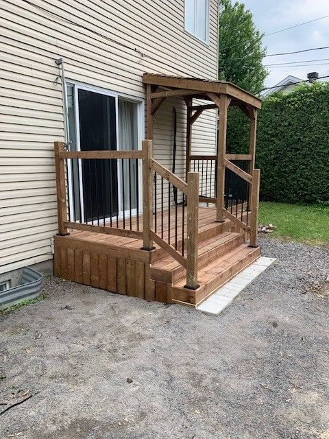 Une terrasse en bois avec des escaliers se trouve devant une maison.