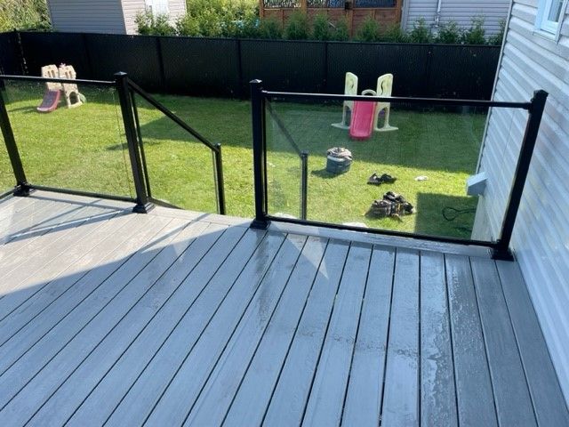 Une terrasse avec une rampe en verre et un toboggan dans la cour arrière.