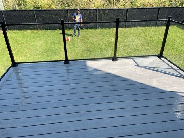 Un homme est debout sur une terrasse avec une clôture en arrière-plan.