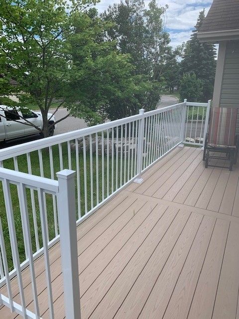 Une terrasse avec une balustrade blanche et une chaise dessus.