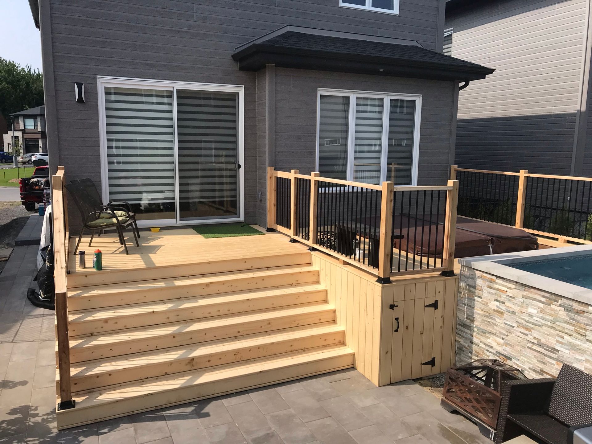 Une terrasse en bois avec des escaliers et un bain à remous dans la cour d'une maison.