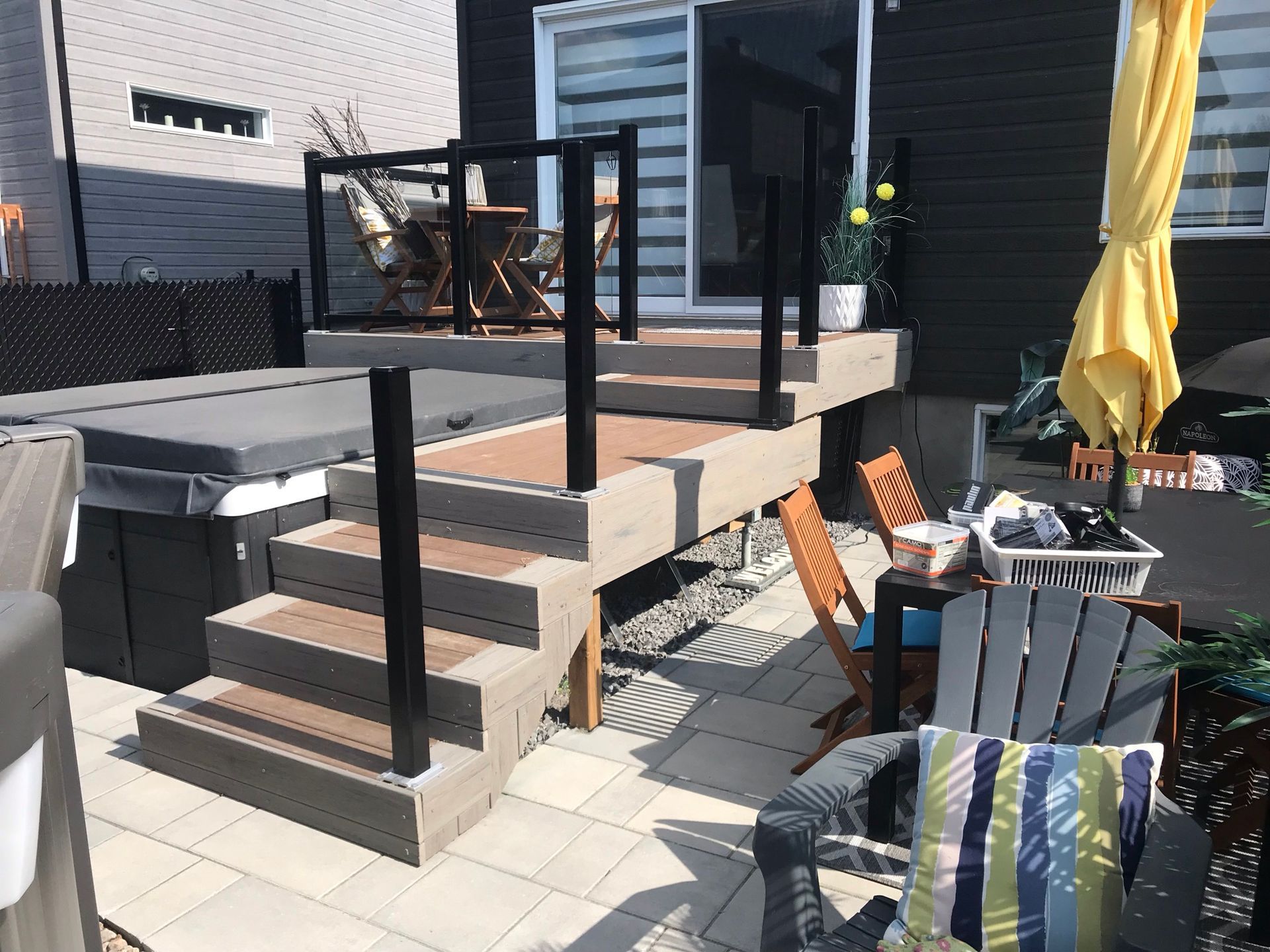 Une terrasse avec des escaliers menant à un bain à remous et un parasol jaune.