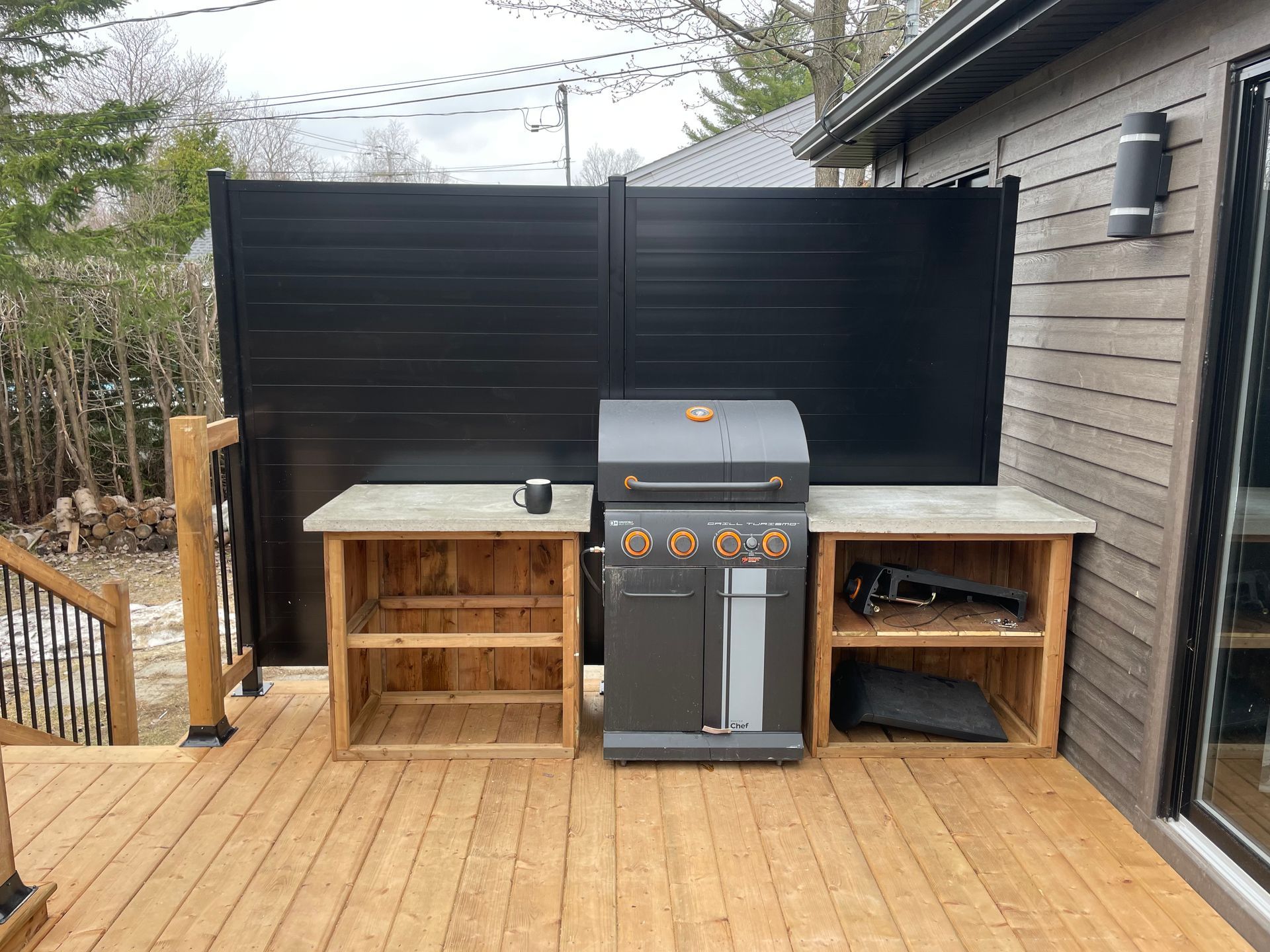Un grill est posé sur une terrasse en bois à côté d'une maison.