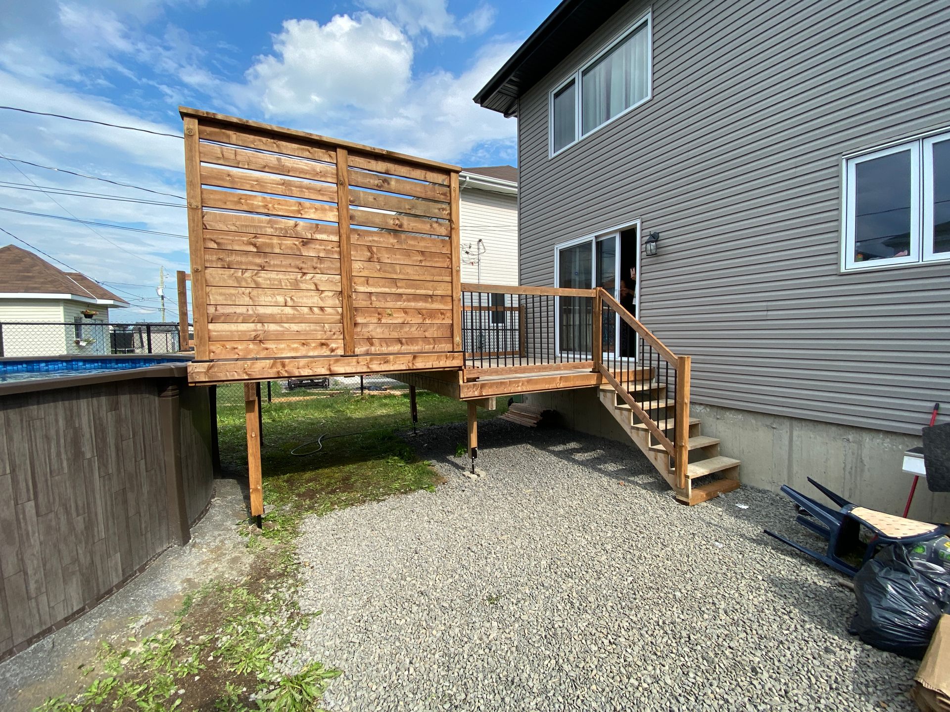 Une terrasse en bois avec des escaliers qui y mènent se trouve dans la cour d'une maison.