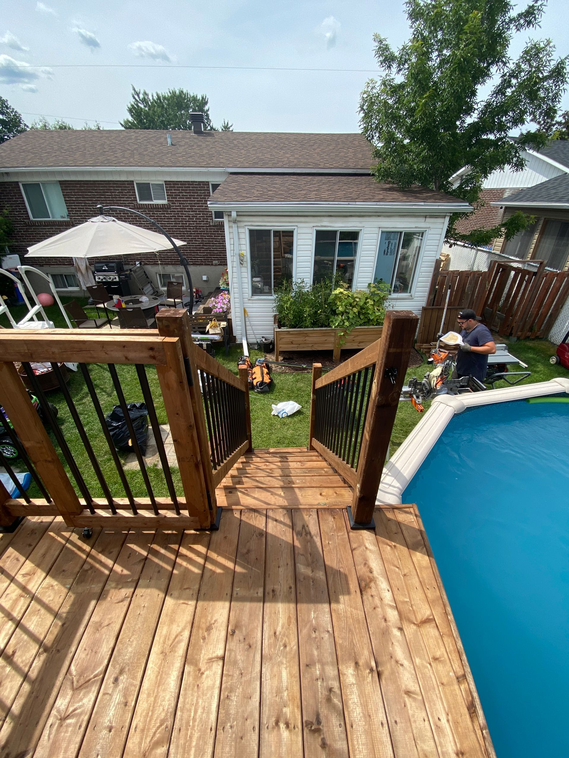 Une terrasse en bois avec des escaliers menant à une piscine dans une cour arrière.