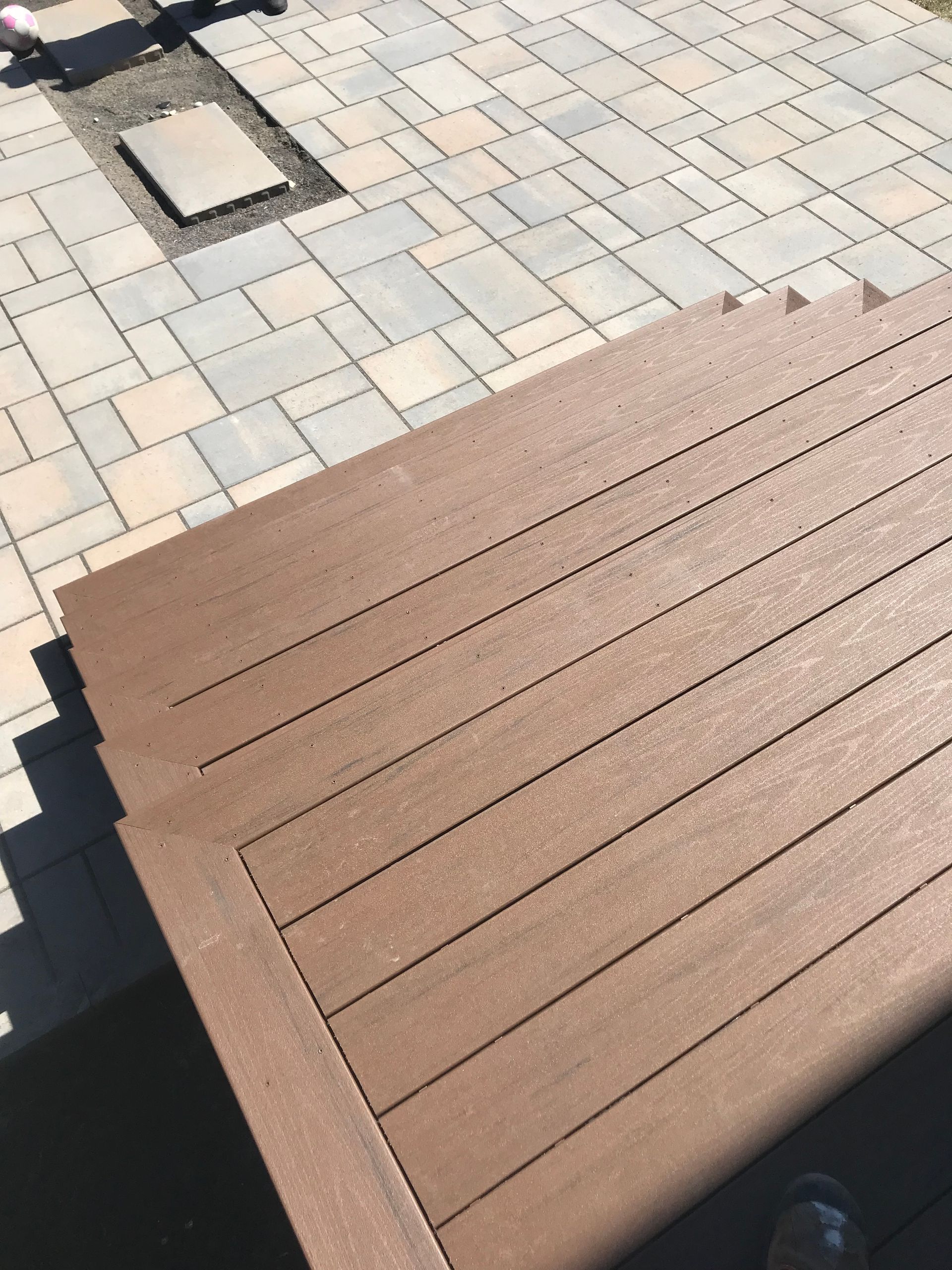 Une terrasse en bois avec une passerelle en brique en arrière-plan