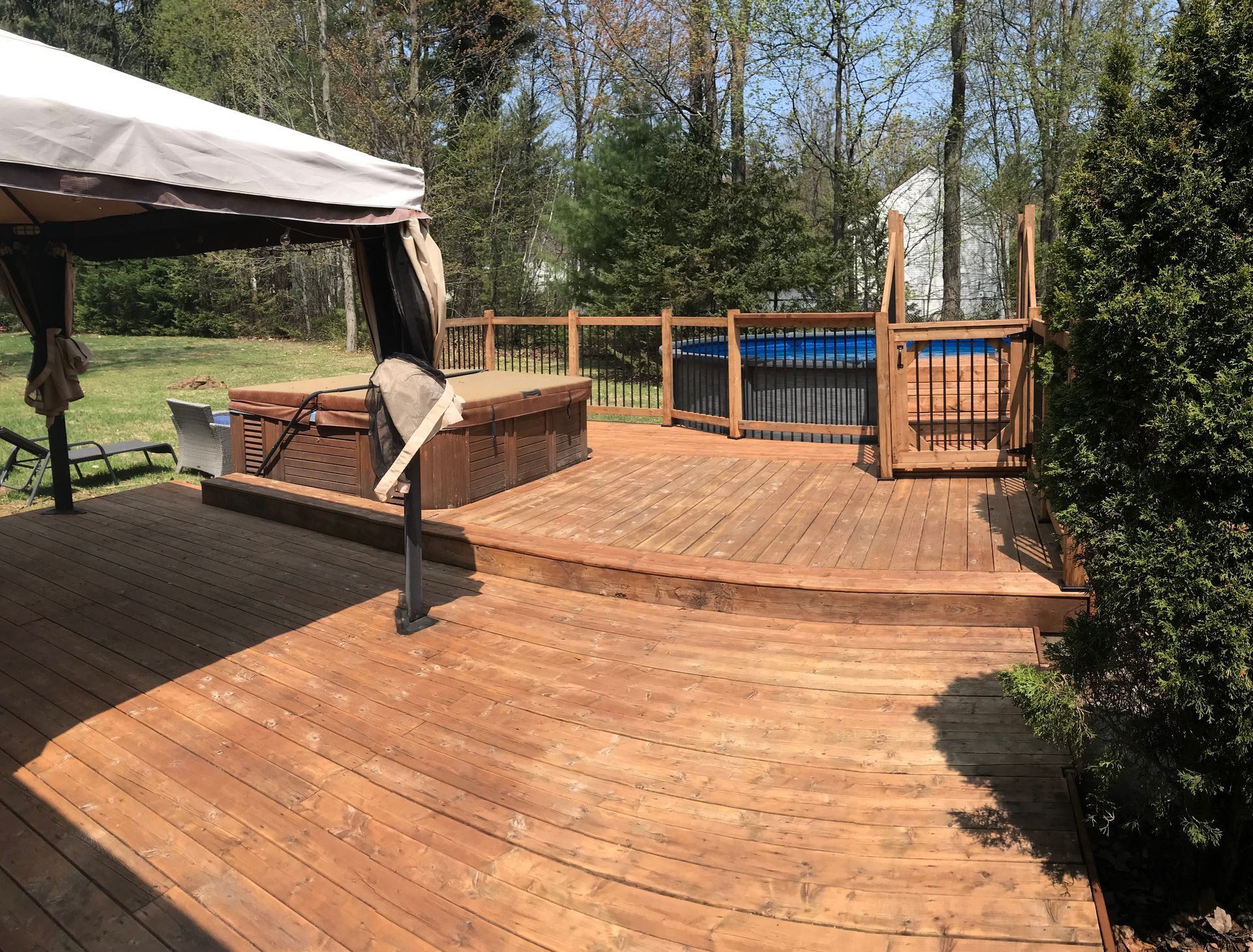 Une terrasse en bois avec un gazebo et un bain à remous.