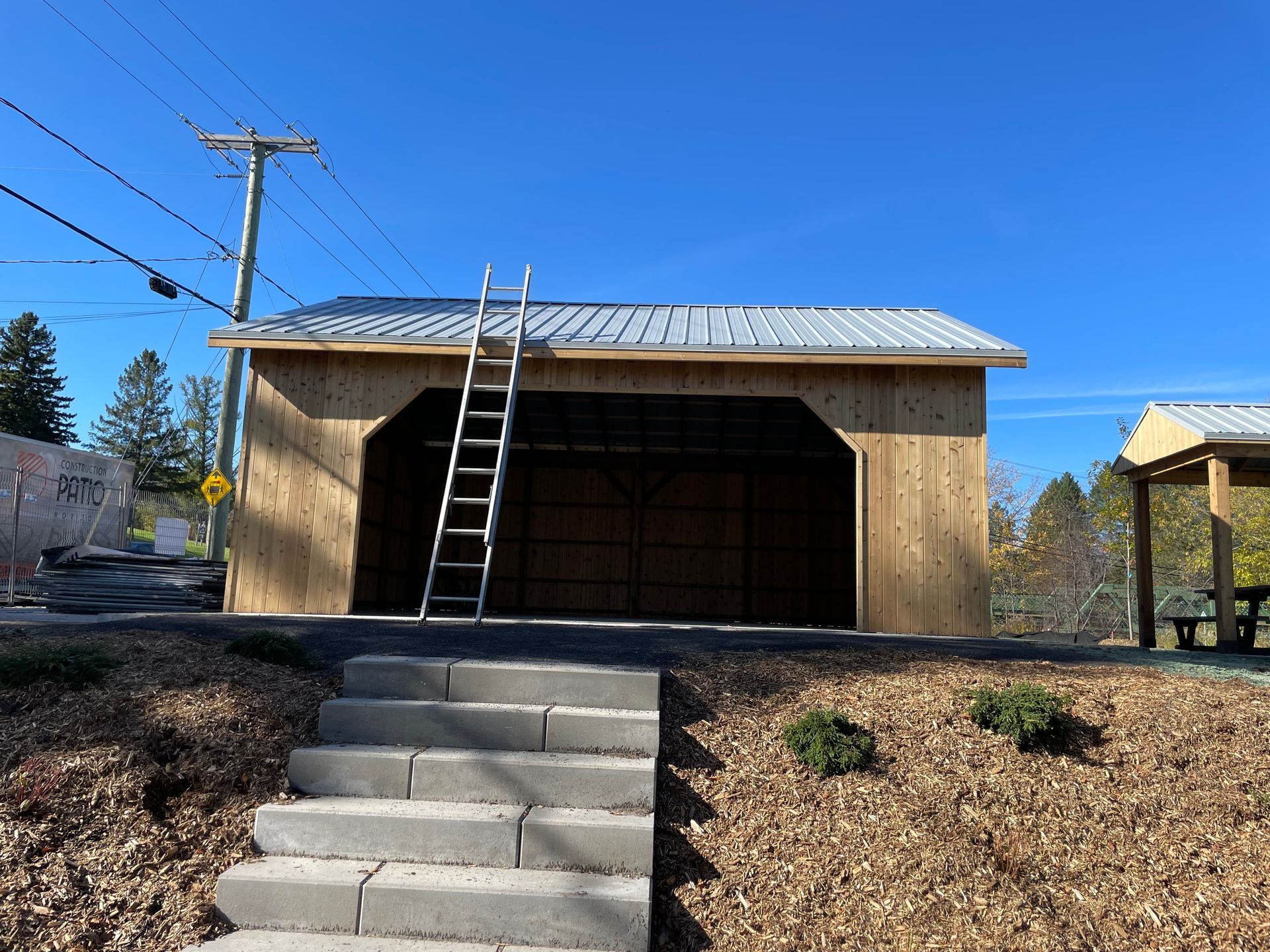 Un garage en bois avec des escaliers qui y mènent et une échelle sur le toit.