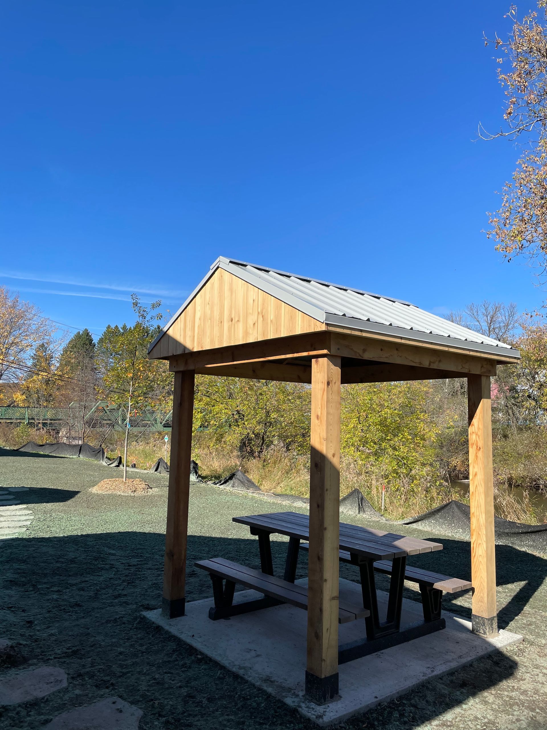 Un belvédère en bois avec une table de pique-nique en dessous dans un parc.