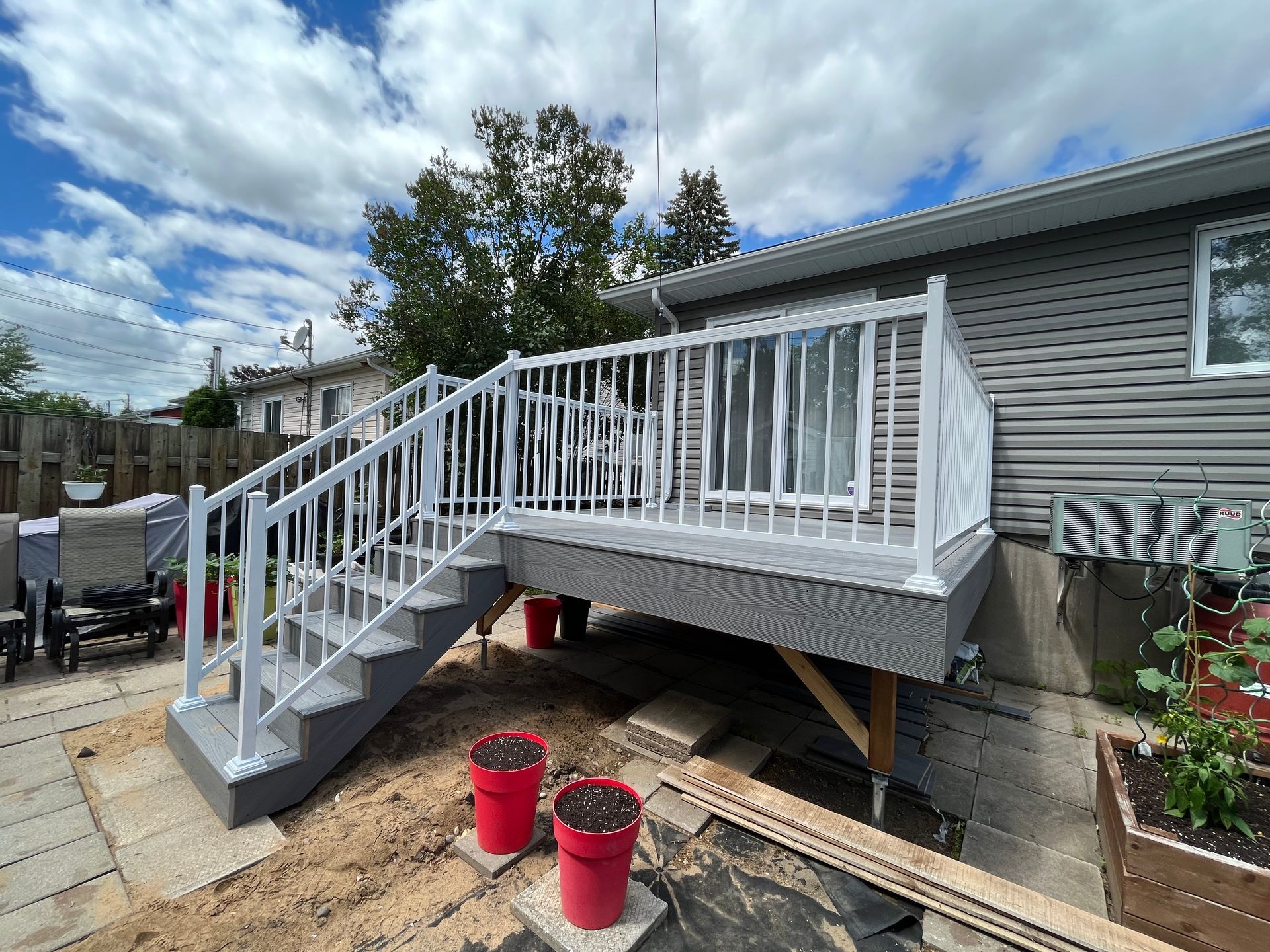 Une terrasse avec des escaliers qui y mènent se trouve dans la cour d'une maison.